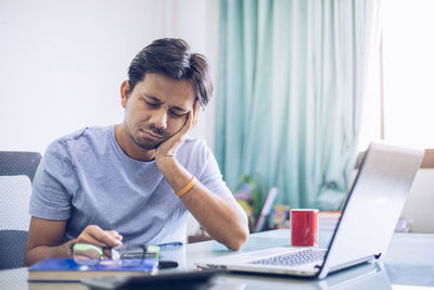 Young man using mobile phone while sitting on table