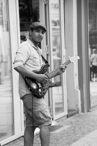 Portrait of street musician playing electric guitar on footpath