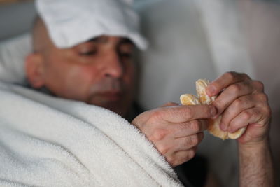 Close-up of man having orange while lying on sofa