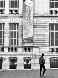 Rear view of man walking on street against building