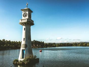 Clock tower amidst lake against sky