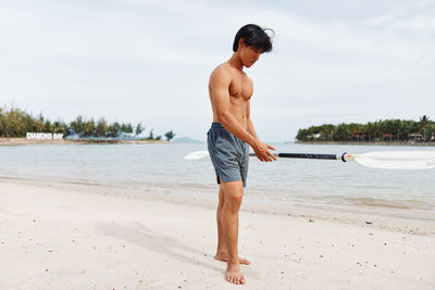 Full length of shirtless man standing at beach