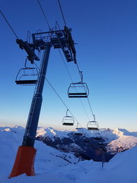 Overhead cable cars on snow covered field against sky