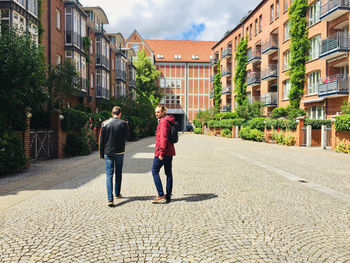 People walking on footpath amidst buildings in city