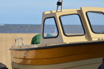 Close-up of yellow ship on sea against sky