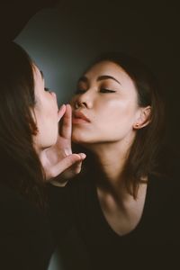 Close-up of mother and daughter against black background