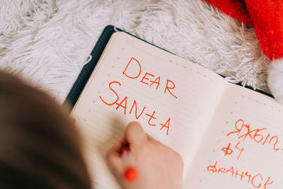 Hands of kid, lying on couch and writing letter in to dear santa. child wish list. dreams new year