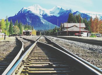 Railroad tracks leading towards snowcapped mountains during winter