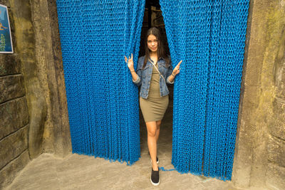 Full length of young woman standing by metal chains