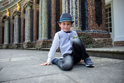 Portrait of boy sitting against building