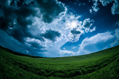 Scenic view of grassy field against cloudy sky