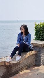 Young woman sitting on retaining wall