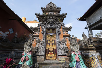 Low angle view of statues on building against sky