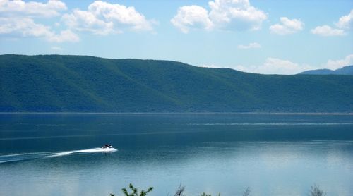 Scenic view of lake by mountains against sky