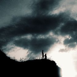 Low angle view of silhouette trees against cloudy sky