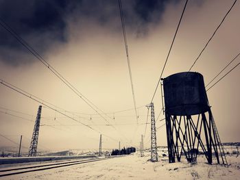 Low angle view of water storage by railroad tracks during winter