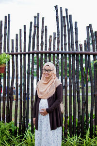 Portraiture of happy pregnant muslim woman caressing belly in park.