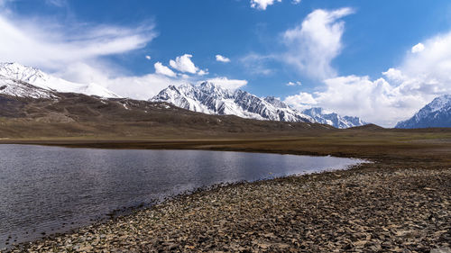 Scenic view of lake by snowcapped mountains against sky