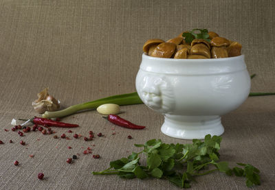 Salted mushrooms in bowl by spices on table