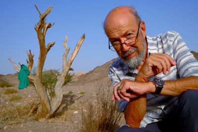 Side view of man sitting on rock