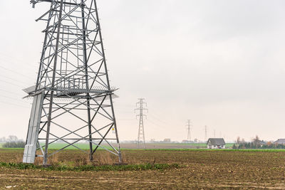 Low angle view of electricity pylon on field against sky