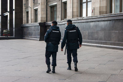 Rear view of men walking on sidewalk in city