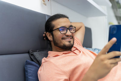 Young man using mobile phone on sofa