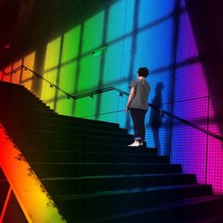 Low angle view of woman standing on steps in illuminated subway