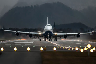 Airplane on illuminated runway against sky at night