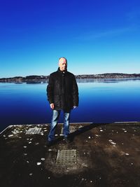 Full length of man standing on pier against blue sky