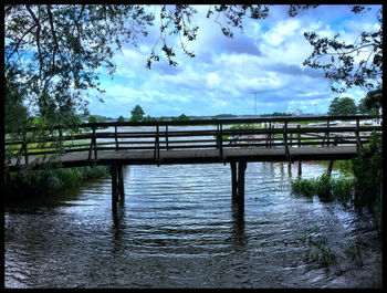 Bridge over river against cloudy sky