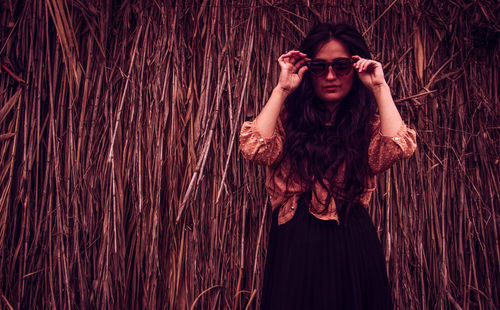 Young woman standing against dried plant