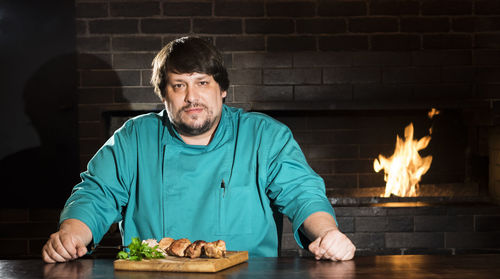 Portrait of chef standing by food against wall