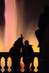 Silhouette people standing by railing against fountain