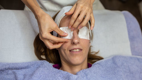 High angle view of woman putting cotton over eyes