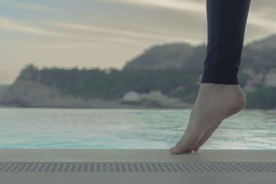 Low section of woman on poolside during sunset