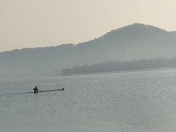 Silhouette person on mountain lake against sky