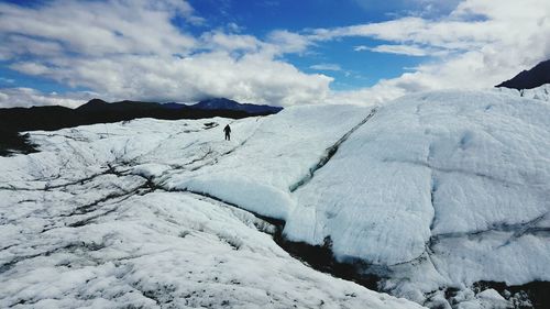 Hiker on glacier against sky