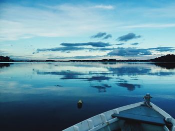 Cropped image of boat moored in calm lake against sky