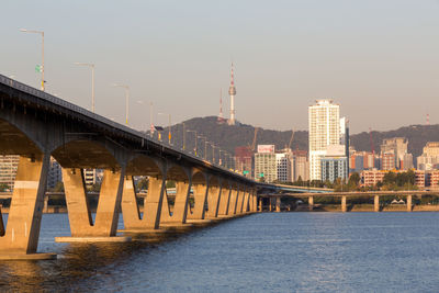 Bridge over river in city against clear sky