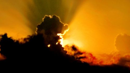 Close-up of silhouette bonfire against sky at sunset