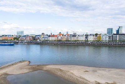 Scenic view of river by buildings against sky