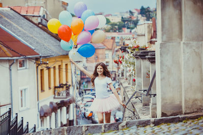 Full length of woman with balloons standing against building