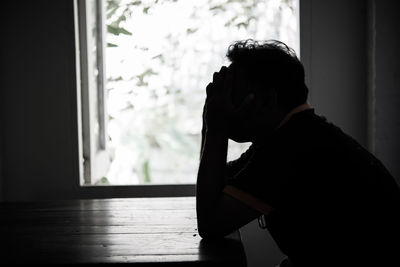 Silhouette depressed man sitting at table