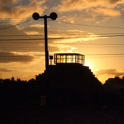 Low angle view of electricity pylon against cloudy sky