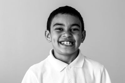 Close-up portrait of smiling boy over white background
