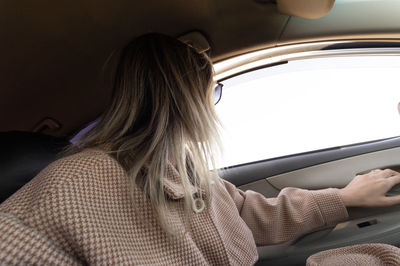 Rear view of woman sitting in car. looking away  through the window