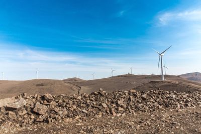 Windmills on landscape against sky