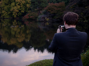 Rear view of man photographing lake