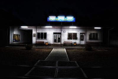 Illuminated street light against building at night